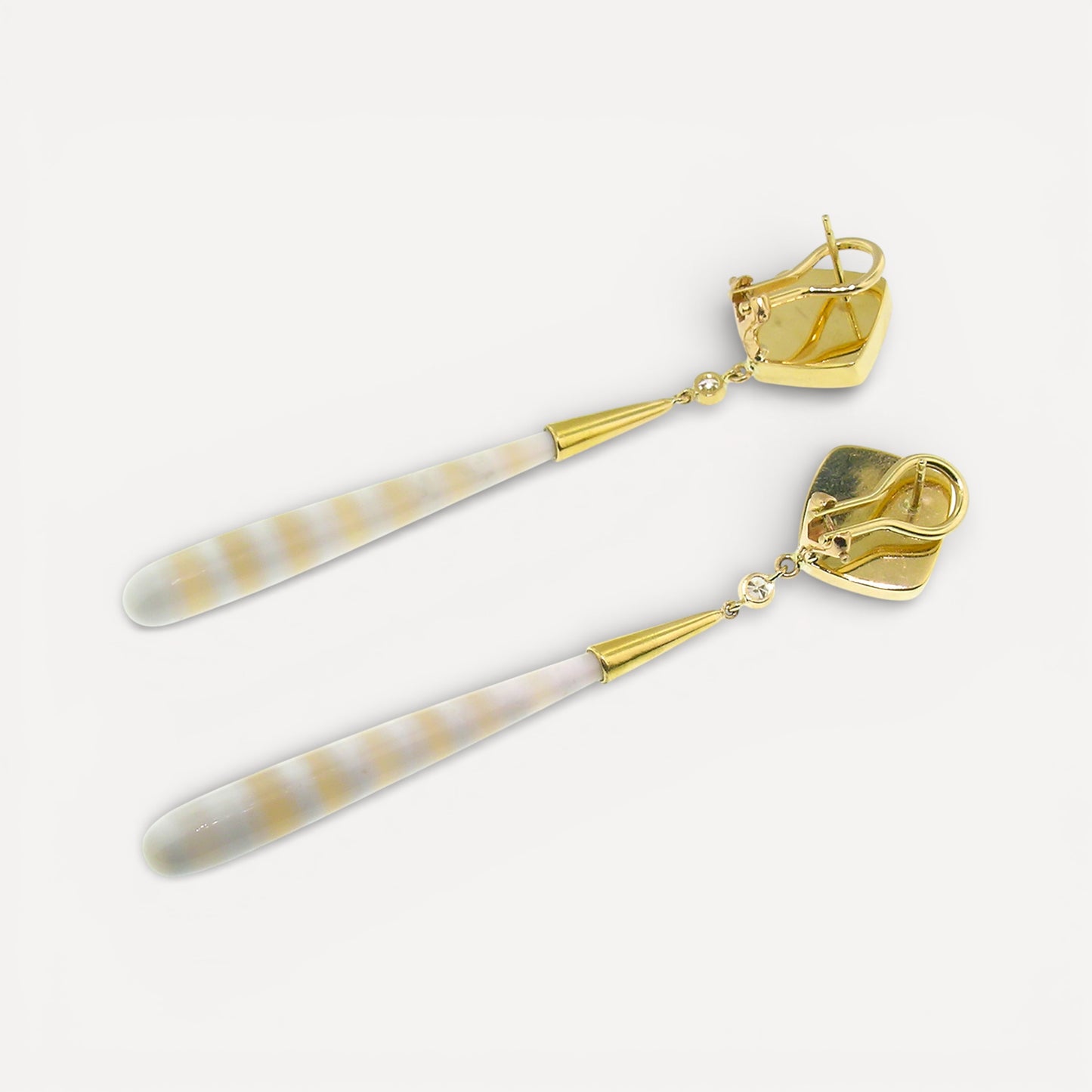 A pair of 18kt gold earrings with pyrite fossil ammonite and German-carved agate which feature alternate bands of creamy white and translucent peach. Made in the USA by Cynthia Scott Jewelry.
