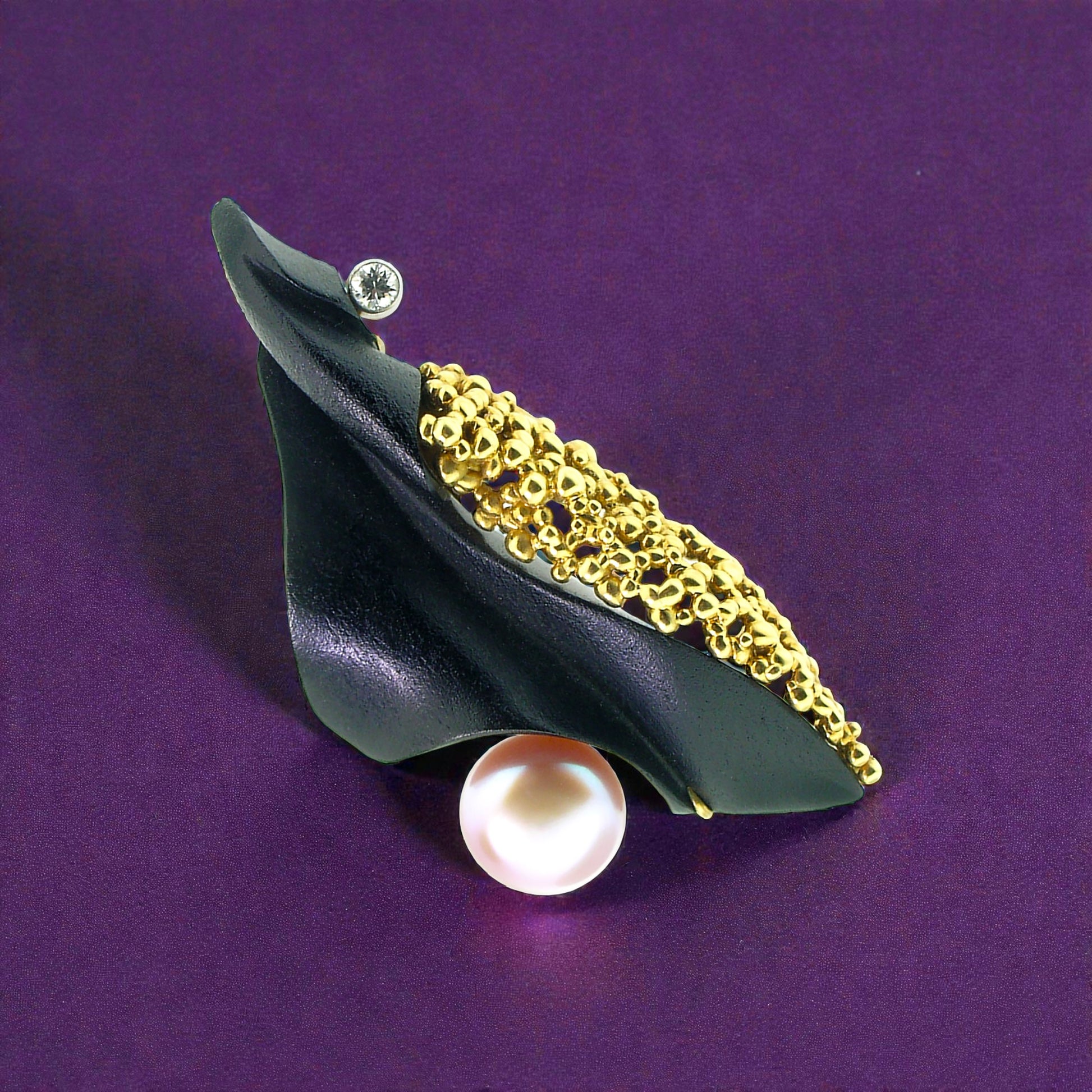 A black chalcedony carving by Steve Walters in an 18kt pendant and brooch with granulation, a diamond, and a pearl by ART Guyon for Cynthia Scott Jewelry.
