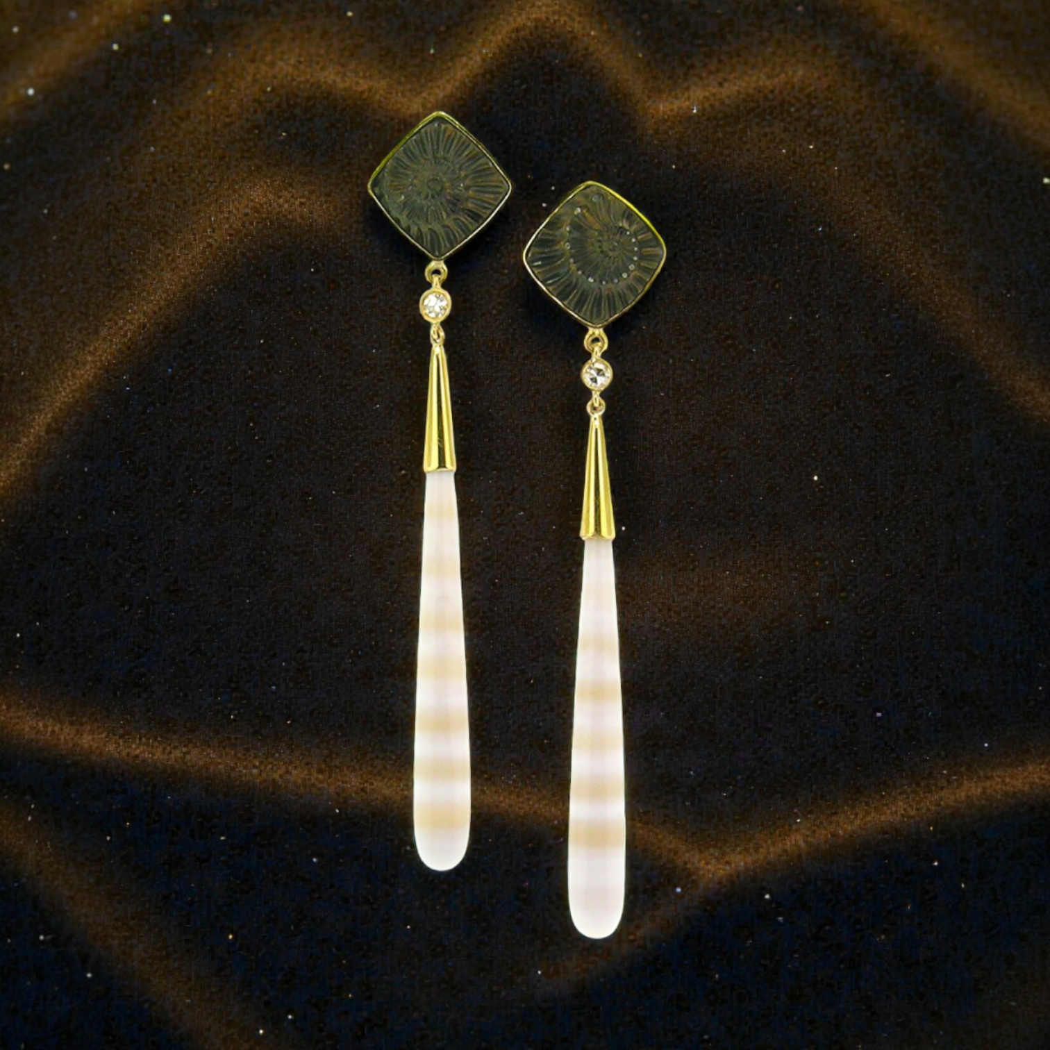 A pair of 18kt gold earrings with pyrite fossil ammonite and German-carved agate which feature alternate bands of creamy white and translucent peach. Made in the USA by Cynthia Scott Jewelry.